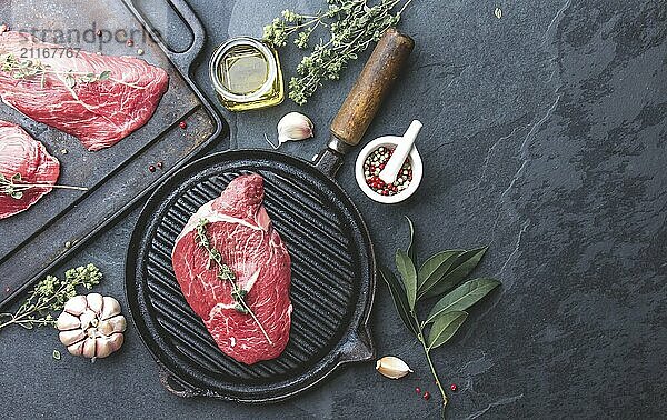 Food  Fresh raw meat. Beef Tenderloin and marbled beef steaks on grill pan and frying board with seasoning  black background top view