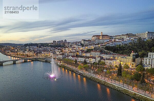 Coimbra drone aerial city view at sunset with colorful fountain in Mondego river and beautiful historic buildings  in Portugal