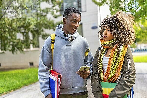 Multi-ethnic friends gathered together using a phone looking at social network content in the campus