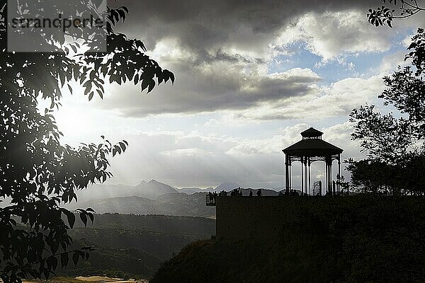 Ronda  malaga  spanien Silhouette einer Gruppe von Menschen auf einer Klippe bei Sonnenuntergang mit Sonnenstrahlen und bewölktem Himmel