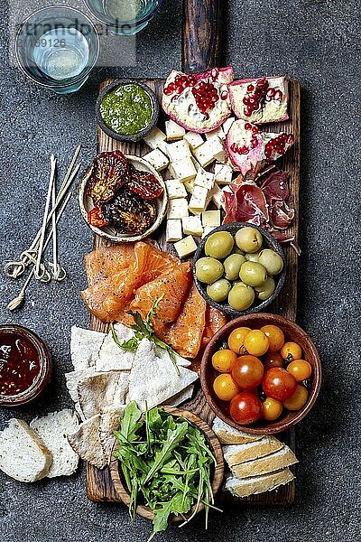 Food  Food  Antipasto. Wine set appetizer. Ham serrano  smoked salmon  dried and fresh tomatoes olive cheese  wine on board. Top view  gray cncrete background