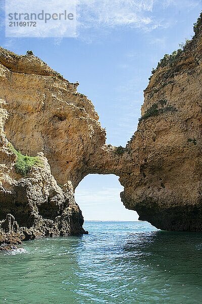 Lagos  Portugal  Ein atemberaubender natürlicher Felsbogen erhebt sich majestätisch über dem ruhigen blauen Wasser des Ozeans unter einem klaren Himmel. Ideal für die Darstellung von Ruhe  der Schönheit der Natur und von Küstenlandschaften  Europa