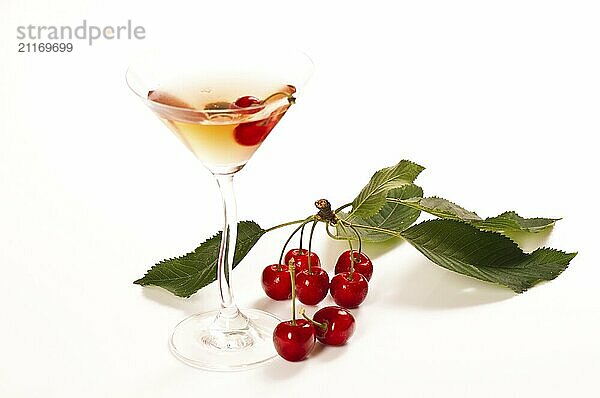 Fresh cherries with cocktail glass against a white background