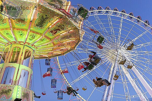 Beleuchtetes Kettenkarussell und Riesenrad bei Nacht mit fröhlichen Menschen  Jahrmarkt  Wellenflug  Cannstadter Volksfest  Stuttgart-Bad Cannstsdt  Baden-Württemberg