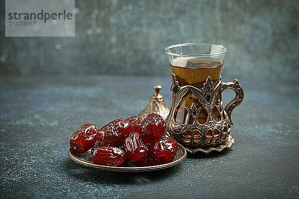 Fastenbrechen mit getrockneten Datteln während des Ramadan Kareem  Iftar Mahlzeit mit Datteln und arabischem Tee im traditionellen Glas  Blickwinkel auf rustikalem blauen Hintergrund. Muslimisches Festmahl  Foodfotografie