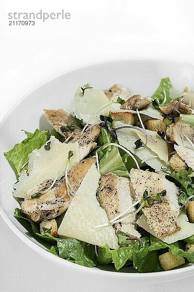 Organic chicken caesar salad with parmesan cheese and croutons on white table background