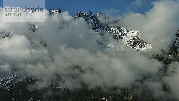 Fliegen durch schöne weiße flauschige Wolken zwischen hohen felsigen Bergen. Dolomiten Alpen Berge  Italien  Europa