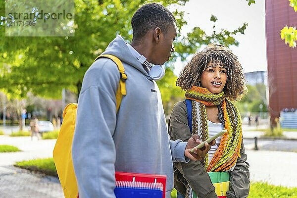 Two young and diverse people using smart phone on the university campus