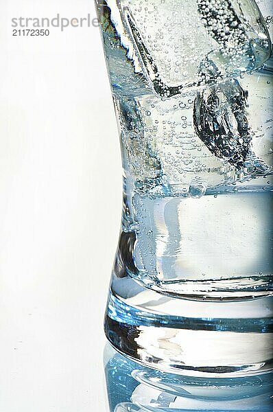 Glass of water against a white background with ice cube cubes