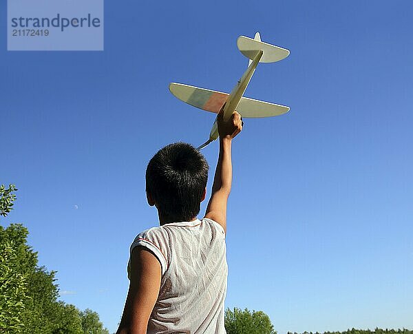 Happy boy running airplane model under blue sky