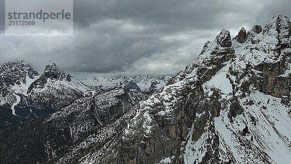 Luftaufnahme von erstaunlichen felsigen Bergen im Schnee unter stimmungsvollen grauen Wolken  Dolomiten  Italien  Europa