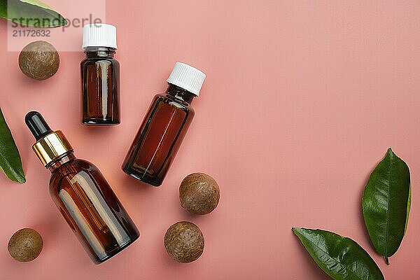 Dropper bottles with macadamia nut essential oil on pink background flat lay design with copy-space