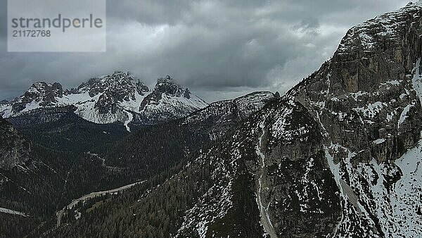 Luftaufnahme von erstaunlichen felsigen Bergen im Schnee unter stimmungsvollen grauen Wolken  Dolomiten  Italien  Europa