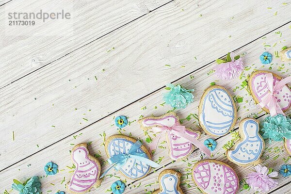 Easter frosted cookies in shape of egg chicken and rabbit on white wooden table background along with sugar sprinkles. Flat lay horizontal mockup