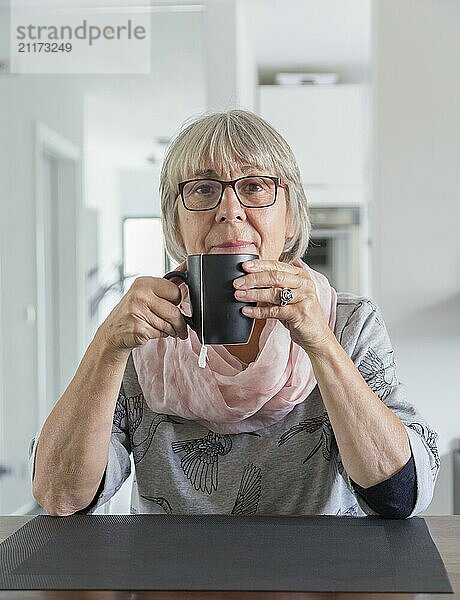 Seniorin hält teetasse und schaut zum betrachter