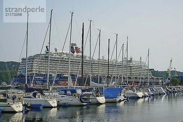 A large cruise ship  Mein Schiff 6  anchored in a quiet harbour with several sailboats in the foreground under a slightly cloudy sky  Sandnes  Fylke Rogaland  Norway  Europe