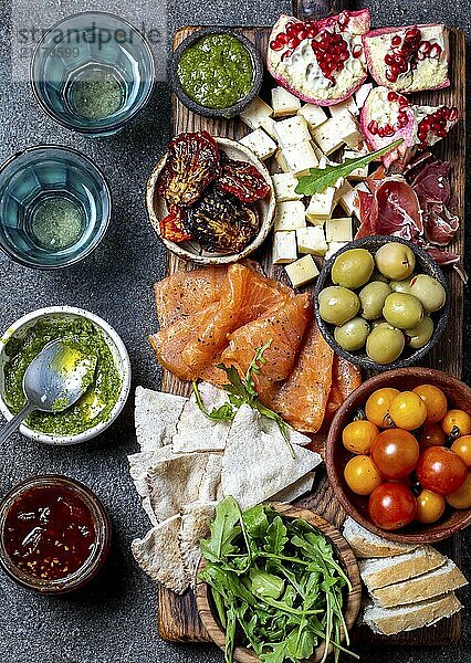 Food  Food  Antipasto. Wine set appetizer. Ham serrano  smoked salmon  dried and fresh tomatoes olive cheese  wine on board. Top view  gray cncrete background