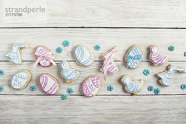 Easter frosted cookies in shape of egg chicken and rabbit on white wooden table background along with sugar sprinkles. Flat lay horizontal mockup