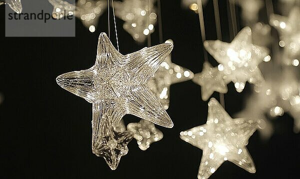 Clear star-shaped lights hanging and glowing brightly against a dark background with a bokeh effect AI generated