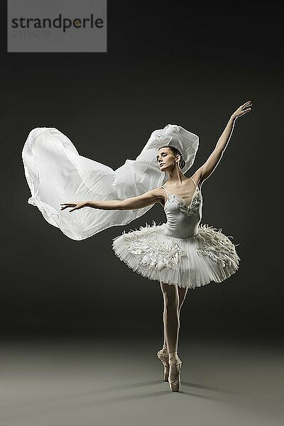 Beautiful ballerina wearing white tutu dancing on pointe and with white cloth view in the dark room