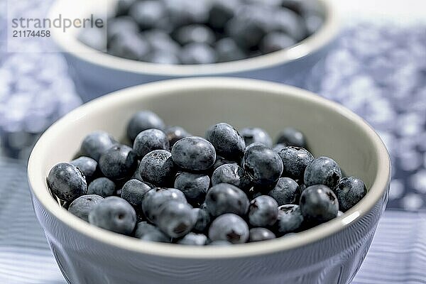 Blueberries in a small grey bowl on a light blue background  close up