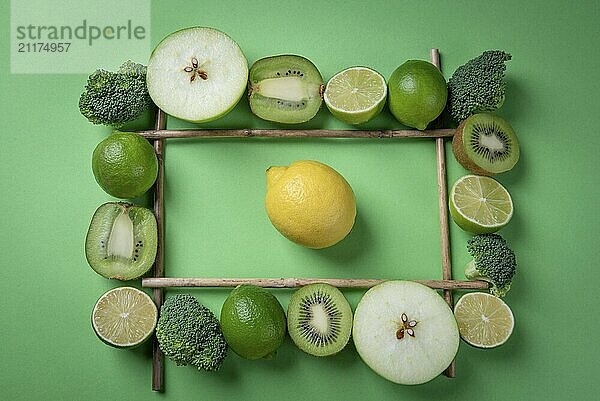 Yellow lemon fruit on green background in the middle of fresh fruits frame. Rich in vitamins food above view