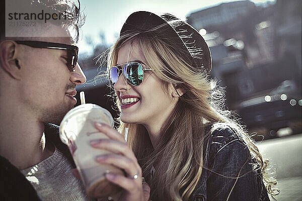 Smiling couple walk at the street in weekend and drink some cocktails