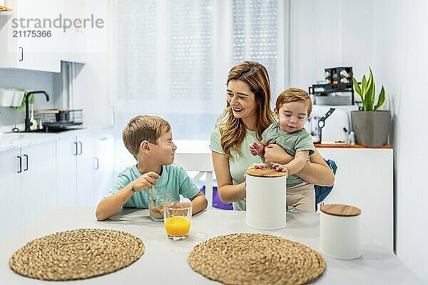 Mutter mit Baby frühstückt mit Schuljunge zu Hause  bevor sie zur Schule geht