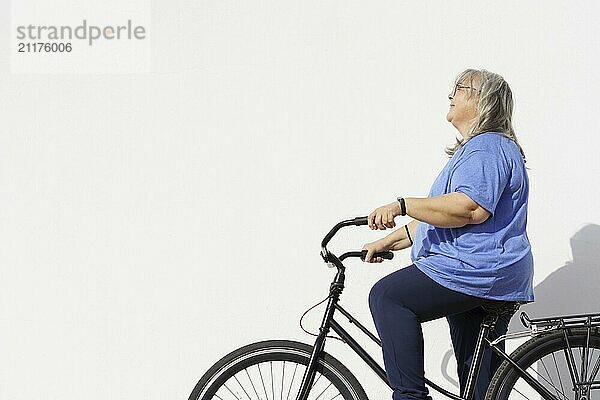 Smiling overweight mature woman riding a retro style bicycle isolated on white background and copy space  exercise concept in the elderly