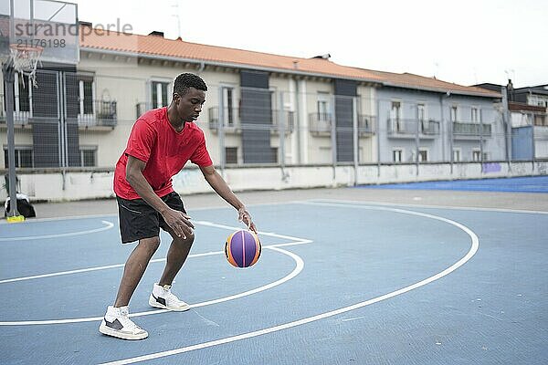 Full length photo with copy space of a young african male basketball player training dribbling outdoors