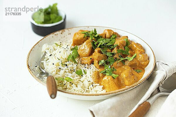 Traditionelles indisches Gericht Hühnercurry mit Basmatireis und frischem Koriander auf rustikalem weißem Teller auf weißem Betonküchentisch  Nahaufnahme mit selektivem Fokus. Indisches Abendessen  Food Fotografie  food photography  food photography