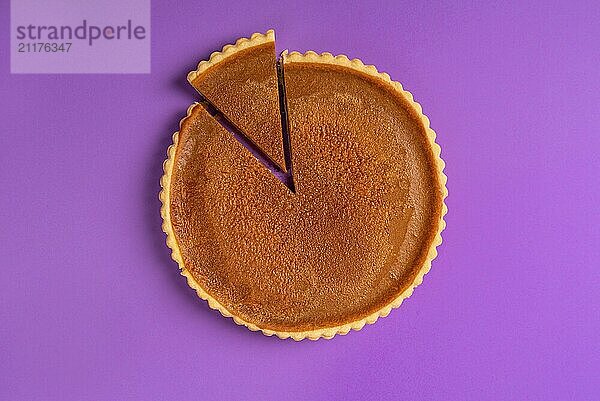 Minimalist image of a pumpkin pie  with one sliced piece and separated  on a purple background. Top view. Traditional dessert. Savory sweet pastry