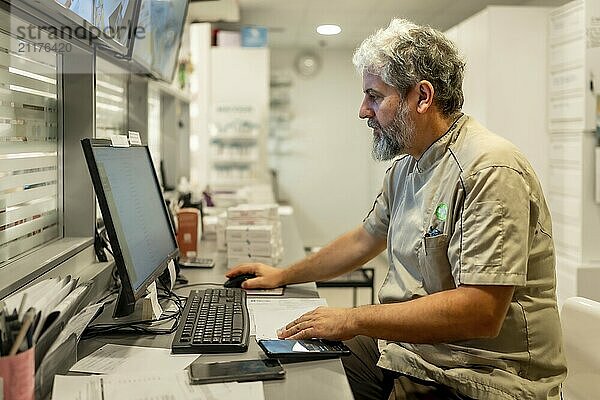 Seitenansicht Porträt eines männlichen reifen Apotheker mit Computer für Papierkram im Büro