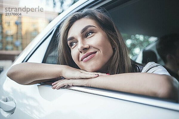 Portrait of cute smiling girl sit in the car and look at the street