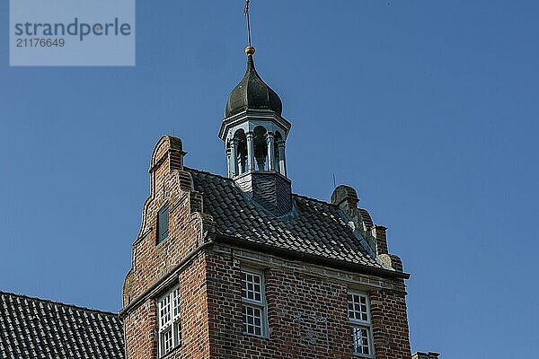 Historic brick tower with bell and weather vane in front of a blue sky  norden  norddeich  north sea  germany