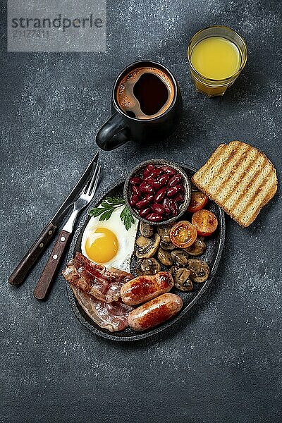 Food  Full fry up English breakfast with fried eggs  sausages  bacon  black pudding  beans  toast and coffee  dark background