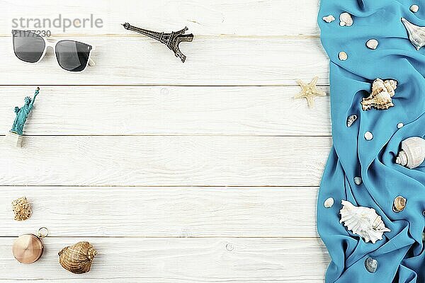 Seashells  sunglasses  compass souvenirs blue fabric and starfish on white planks vacation planning background flat lay with copy-space