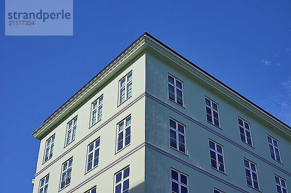 A green corner of a building with many windows against a clear blue sky  Bergen  Vestland  Norway  Europe