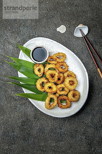 Food  Food  Fried squids rings on white plate decorated with tropical leaves  gray concrete background  top view