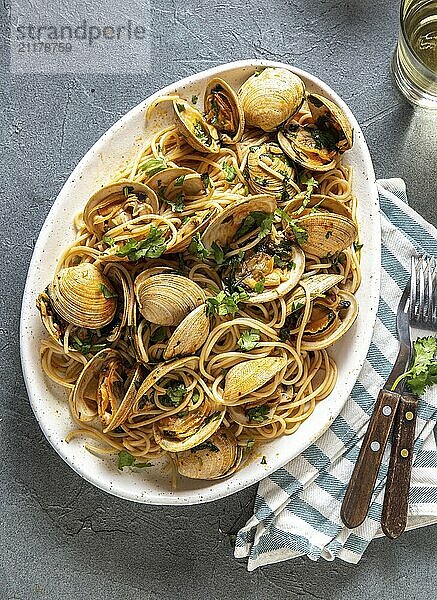 Lebensmittel  Meeresfrüchte Pasta. ITALIENISCHE SPAGHETTI ALLE VONGOLE. Venusmuscheln Spaghetti auf weißem Teller mit Weißwein  grauer Hintergrund. Ansicht von oben