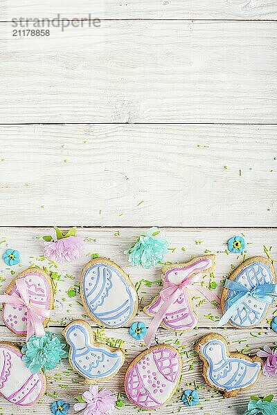 Sugar sprinkles and Easter frosted cookies in shape of egg chicken and rabbit on white wooden table background. Flat lay vertical mockup with copy space