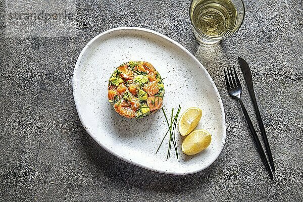 Food  Food  PERUVIAN FOOD. Salmon ceviche with avocado  spring onion and lemon on white plate served with white wine