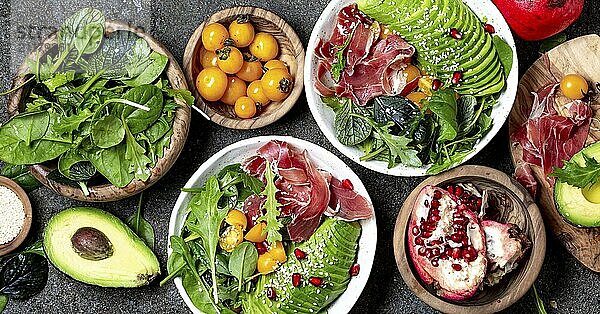 Food  Food  Low carbs bowl. Fresh salad with green spinach  rucola  avocado an ham serrano in white bowl  gray background  top view