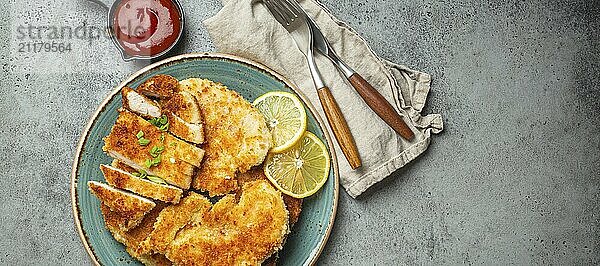 Knusprige Panko paniert gebratenes Hähnchenfilet mit grünem Salat und Zitrone schneiden auf Teller auf grauem Hintergrund Tabelle mit Ketchup von oben. Japanische Art frittierte beschichtete Hähnchenbrust  Platz für Text  Food Fotografie  food photography  food photography