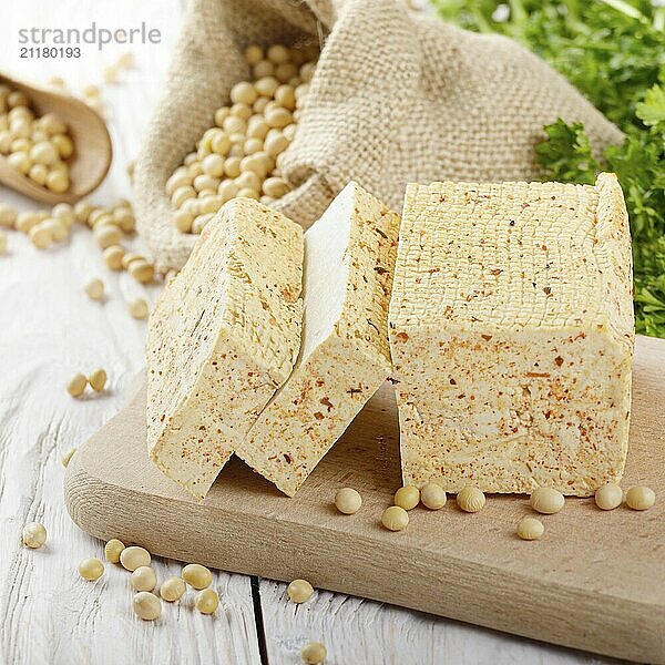 Soy Bean curd tofu on cutting board and in hemp sack on white wooden kitchen table. Non-dairy alternative substitute for cheese