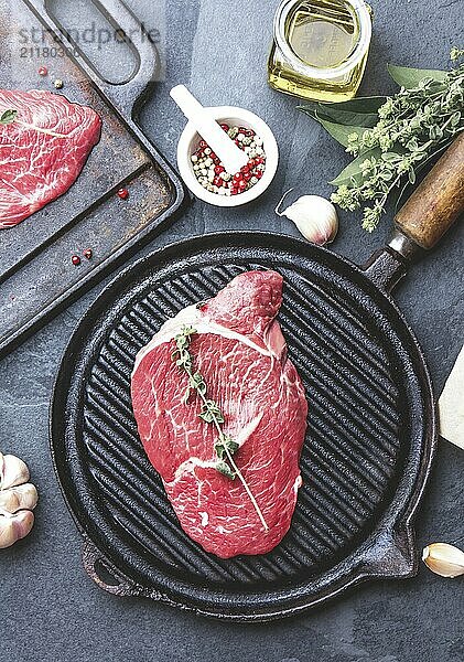 Food  Fresh raw meat. Beef Tenderloin and marbled beef steaks on grill pan and frying board with seasoning  black background top view