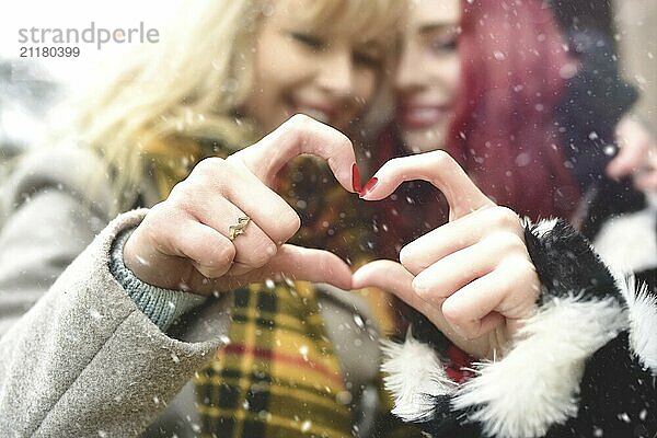 Lesbian couple making heart with hands  open relationship in love. love concept. friendship concept. snowy effect