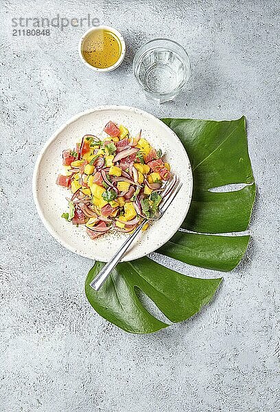 Food  Tropical Hawaiian tahitian tuna mango salad on white plate on tropical monstera leafe