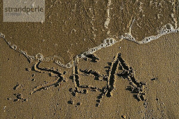 Turkish sea shore with word sea written on the sand washed by waves high angle close up view