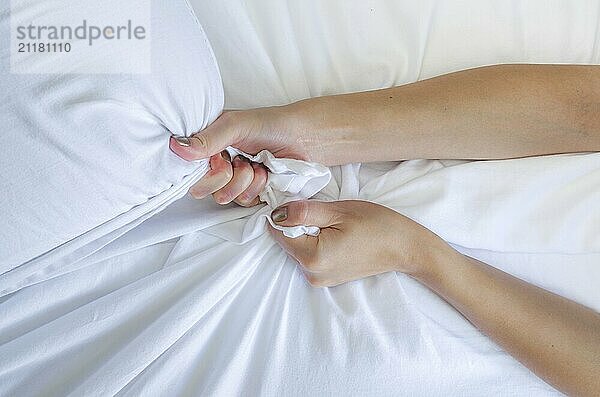 Hand sign orgasm of woman on white bed  Hand of female pulling white sheets in ecstasy  feeling and emotion concept